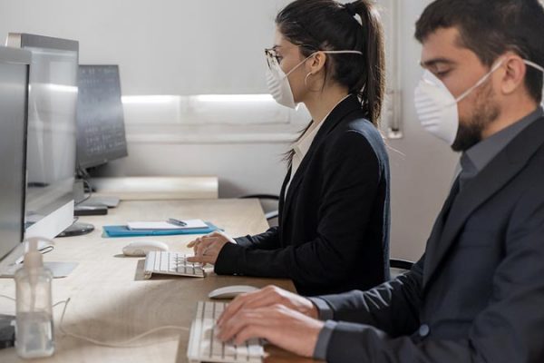 Lavoratori in ufficio con mascherina per tutela COVID 19